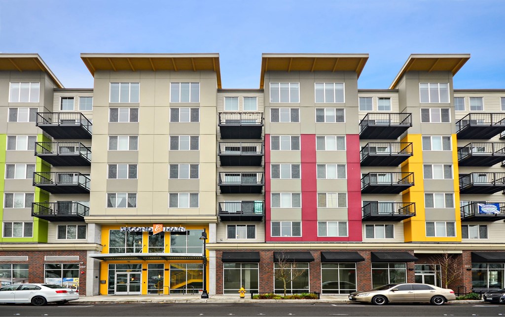A multi-story apartment building with balconies and a storefront at the ground level.