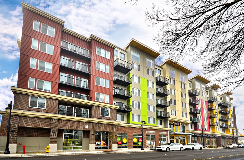 A row of multi-story apartment buildings with balconies and storefronts on the ground level.