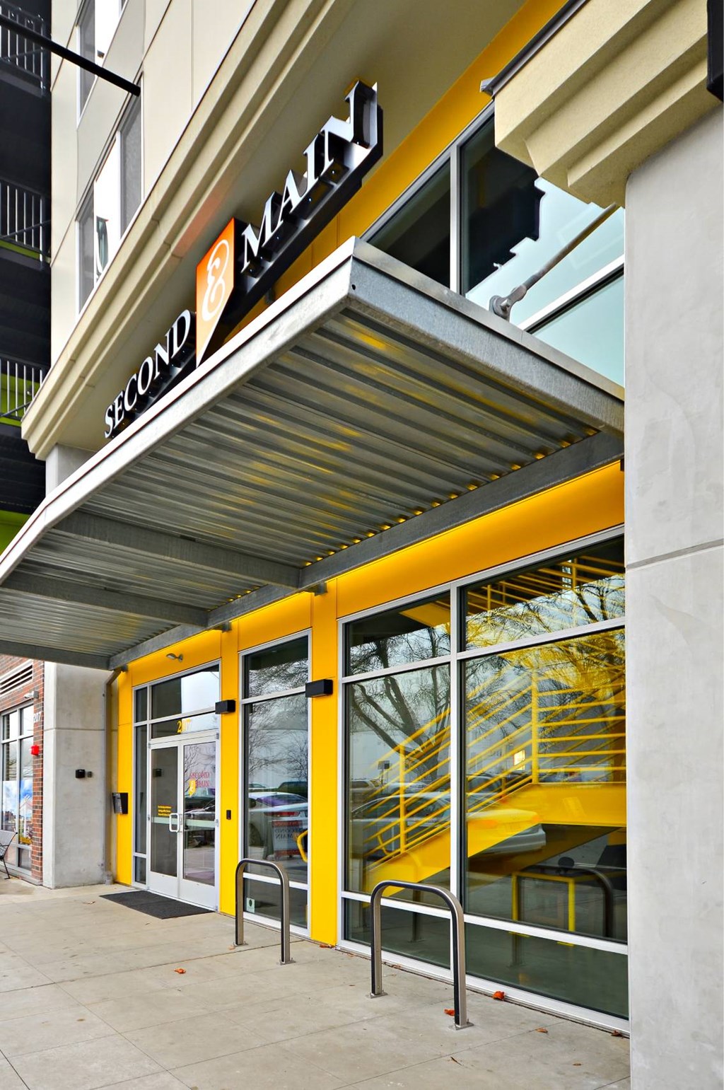 The entrance to a building with a yellow awning and glass doors.
