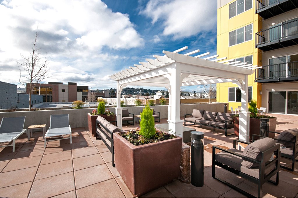 A patio with a white pergola and furniture.