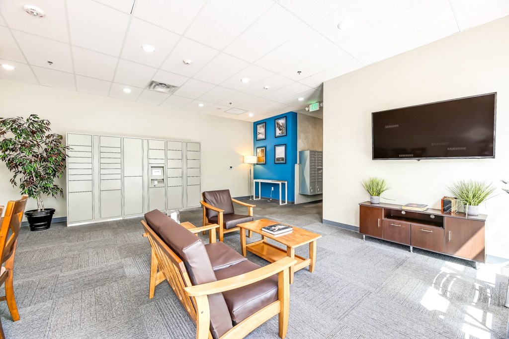A waiting room with brown leather chairs and a flat screen TV mounted on the wall.