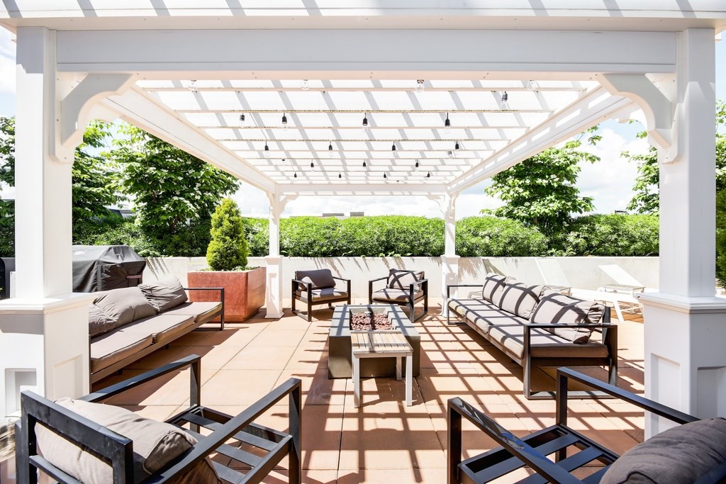 A white pergola with a patio furniture set underneath.
