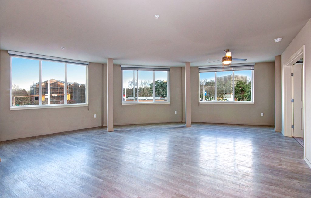A large empty room with wooden floors and windows.