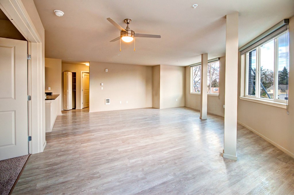 A spacious room with a ceiling fan and wooden flooring.