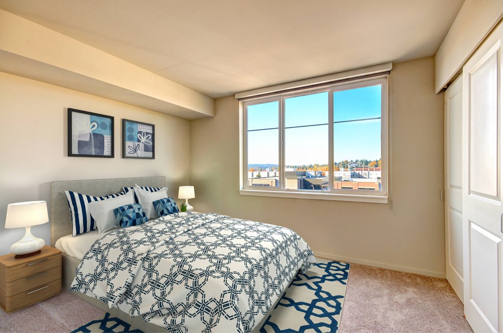 A bedroom with a large bed and a window overlooking a cityscape.