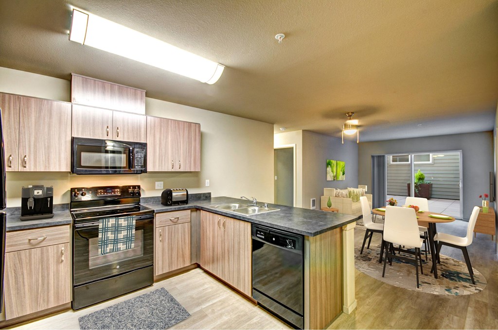 A modern kitchen with wooden cabinets and black appliances.
