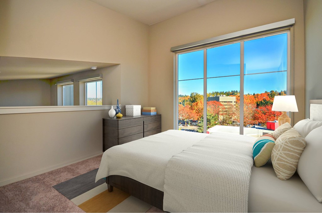 A bedroom with a large bed and a view of the outdoors through a large window.