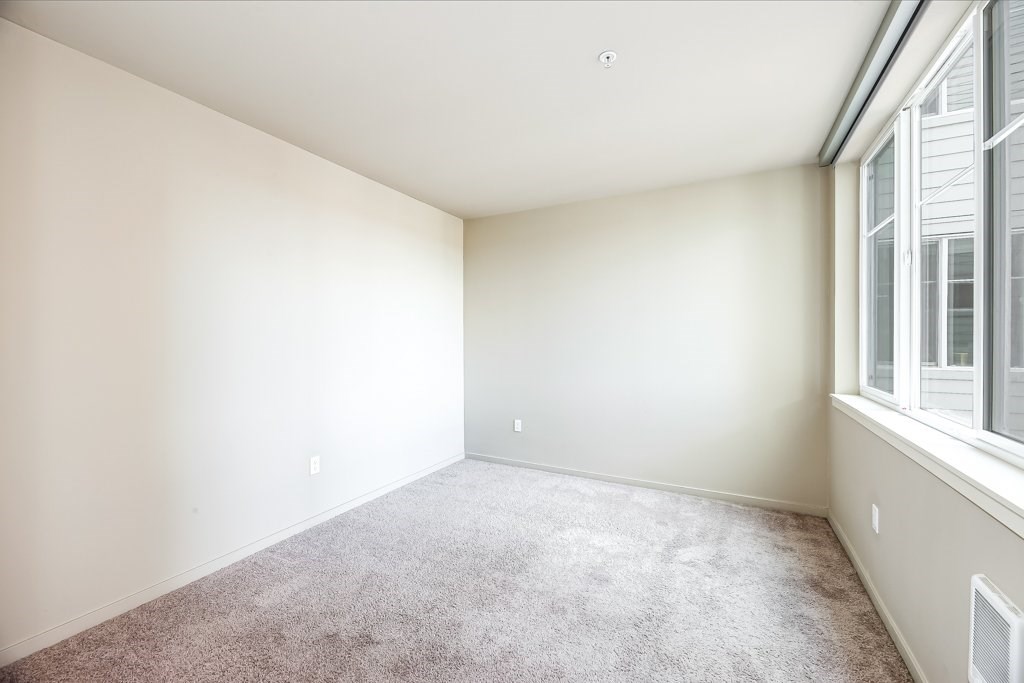 A room with a carpeted floor and a window on the right side.