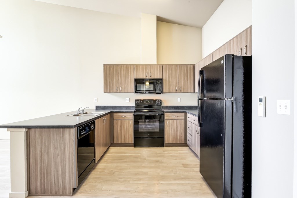 A kitchen with black appliances and wooden cabinets.