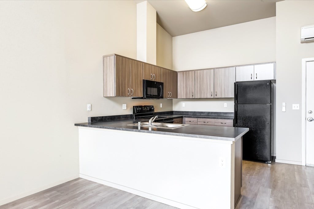 A kitchen with a black refrigerator and white countertops.