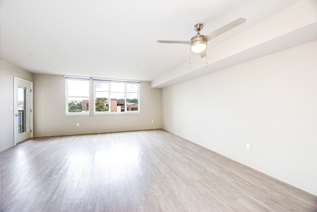 Empty room with a ceiling fan and wooden flooring.