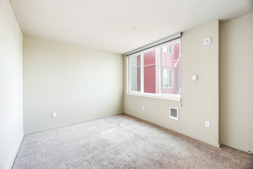 A room with a window and a carpeted floor.