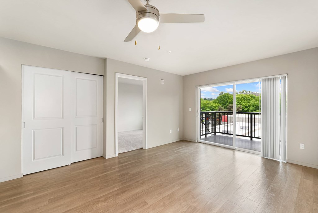 A room with a ceiling fan and sliding glass doors.