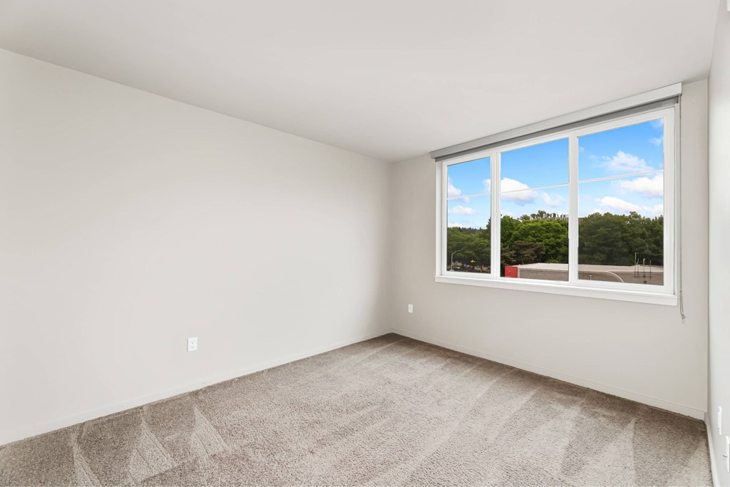 A room with a large window showing a view of trees and sky.