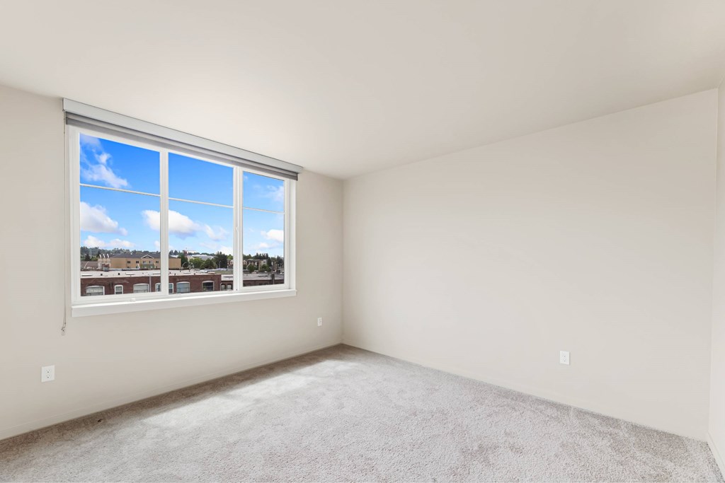 A room with a large window and carpeted floor.