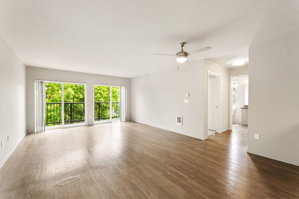 A room with a ceiling fan and sliding glass doors.