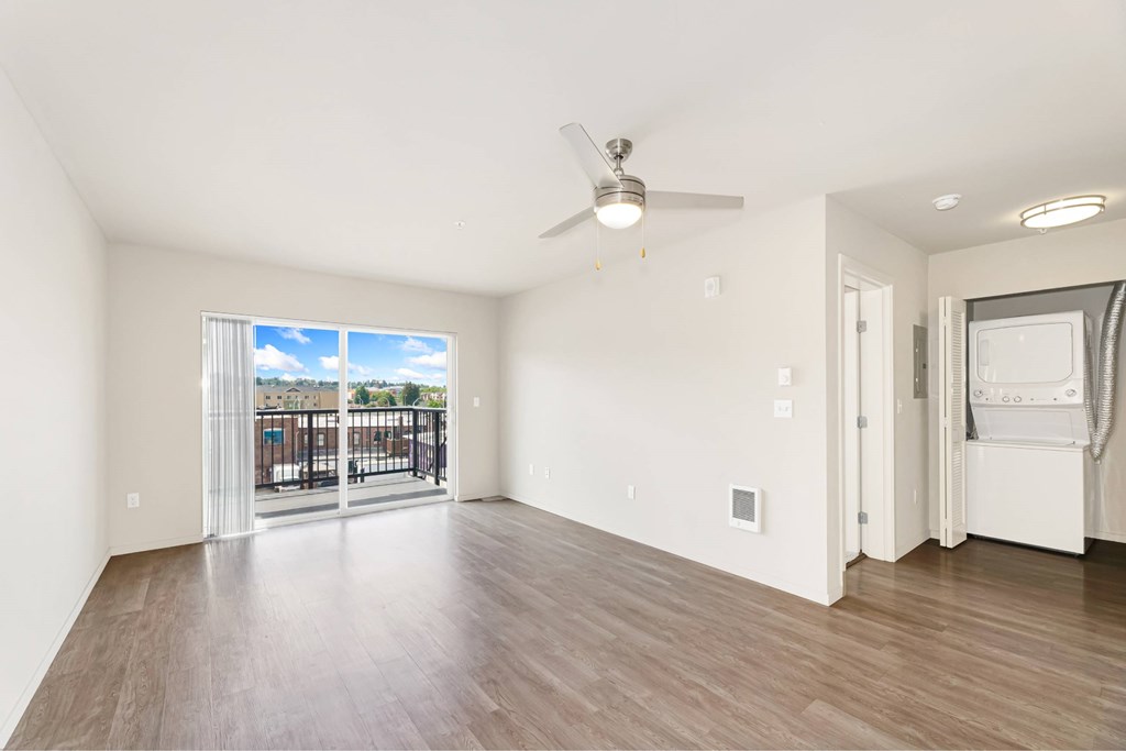 A spacious room with a ceiling fan and sliding glass doors leading to a balcony.