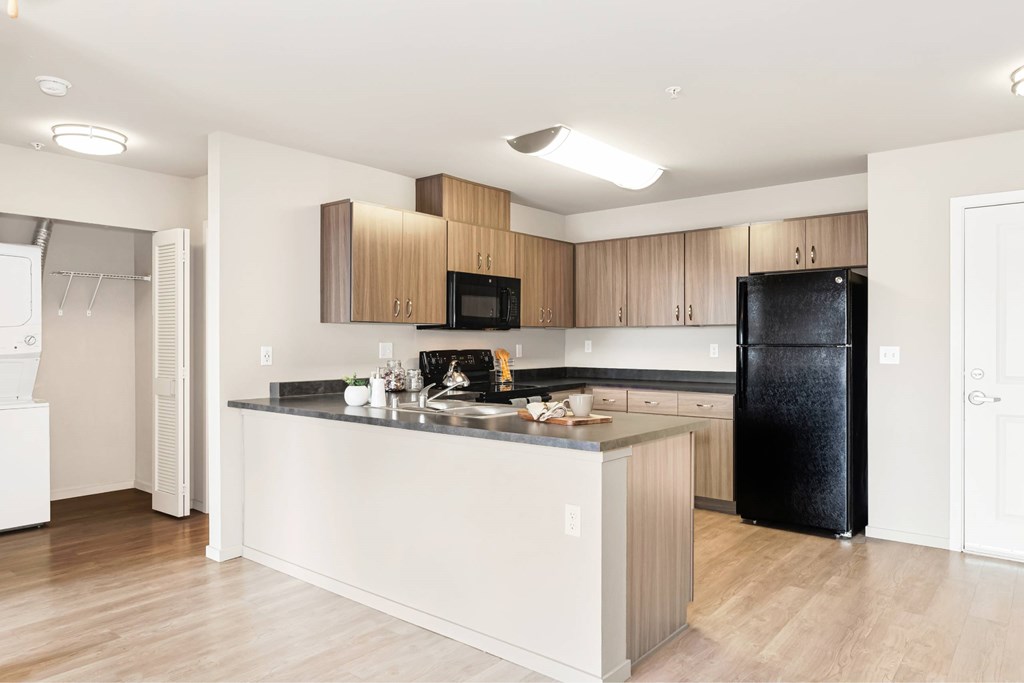 A kitchen with a black fridge and wooden cabinets.