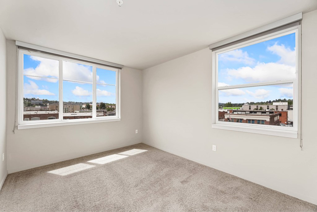 A room with two windows overlooking a cityscape.