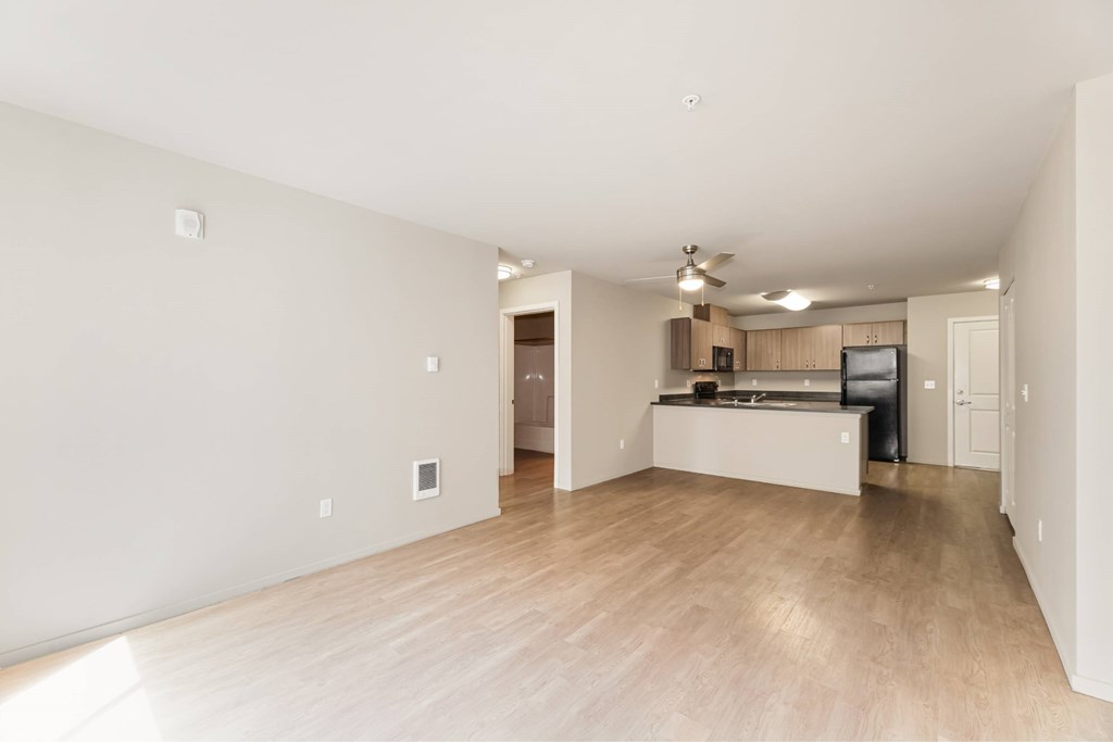 A spacious living room with a kitchen in the background.