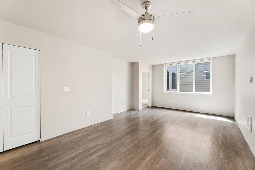 A room with a ceiling fan and wooden flooring.