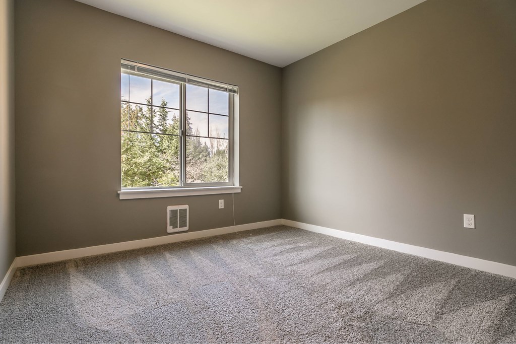 A room with a large window and carpeted floor.