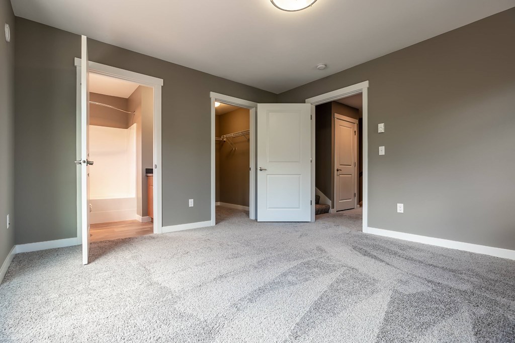 A room with a carpeted floor and three open doors.