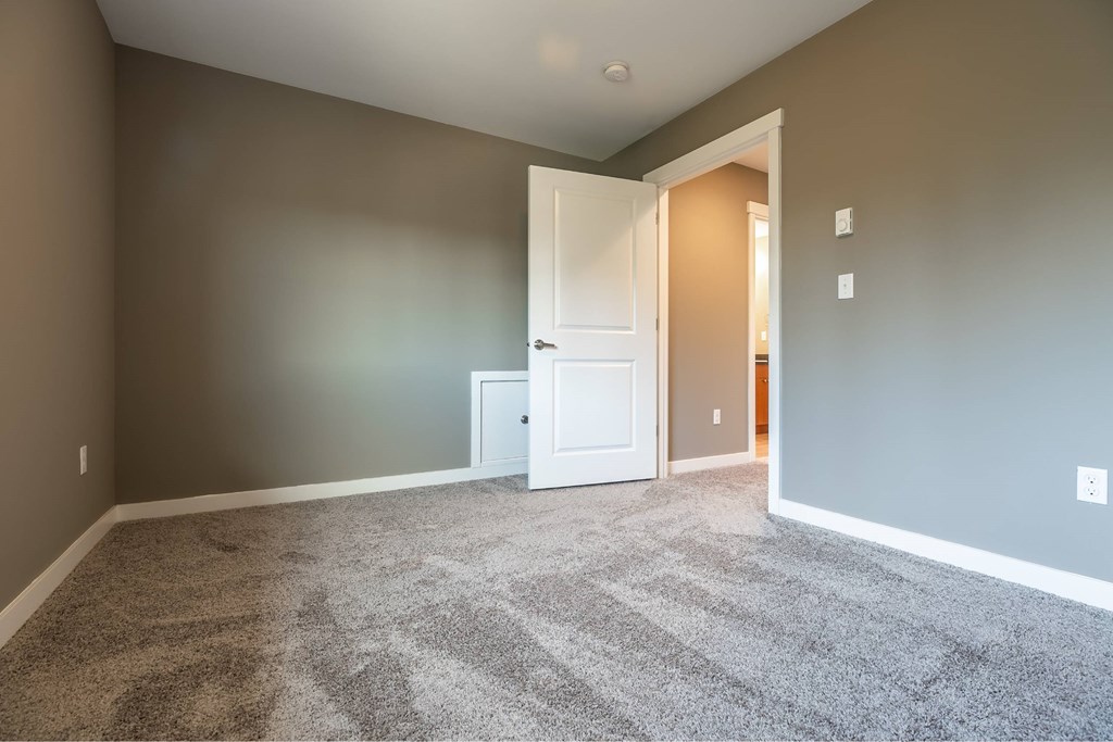 A room with a carpeted floor and a white door.