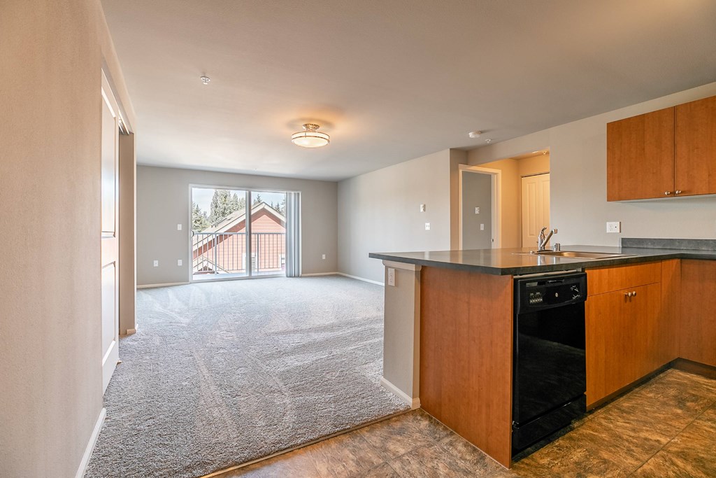 A kitchen with a black dishwasher and wooden cabinets.