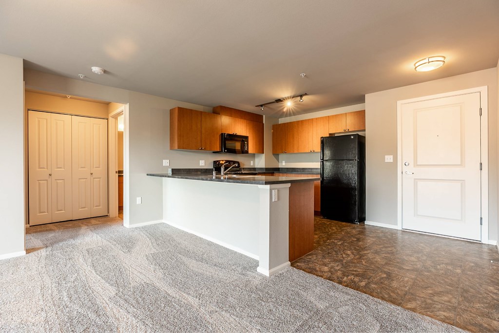 A kitchen with a black refrigerator and wooden cabinets.