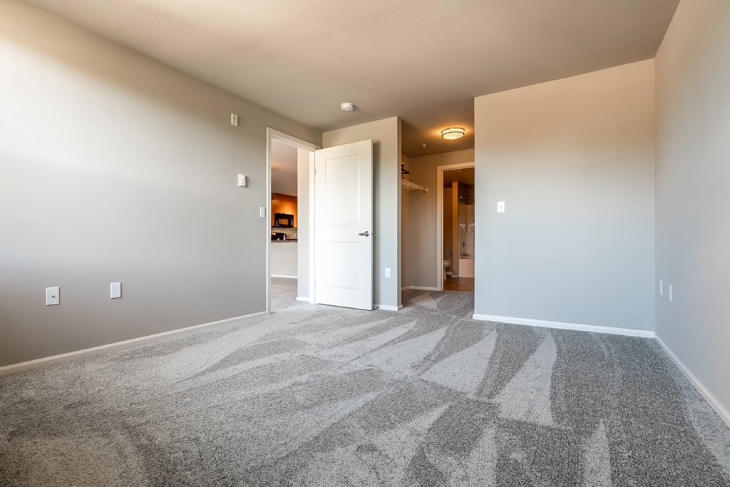 A hallway with a carpeted floor and white walls.