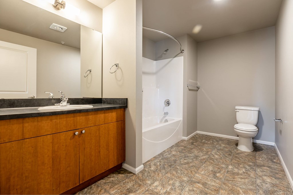 A bathroom with a toilet, sink, and mirror.