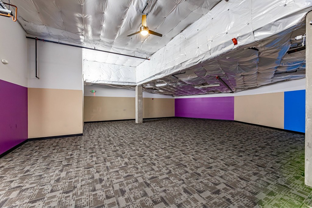A room with a carpeted floor and a ceiling fan.