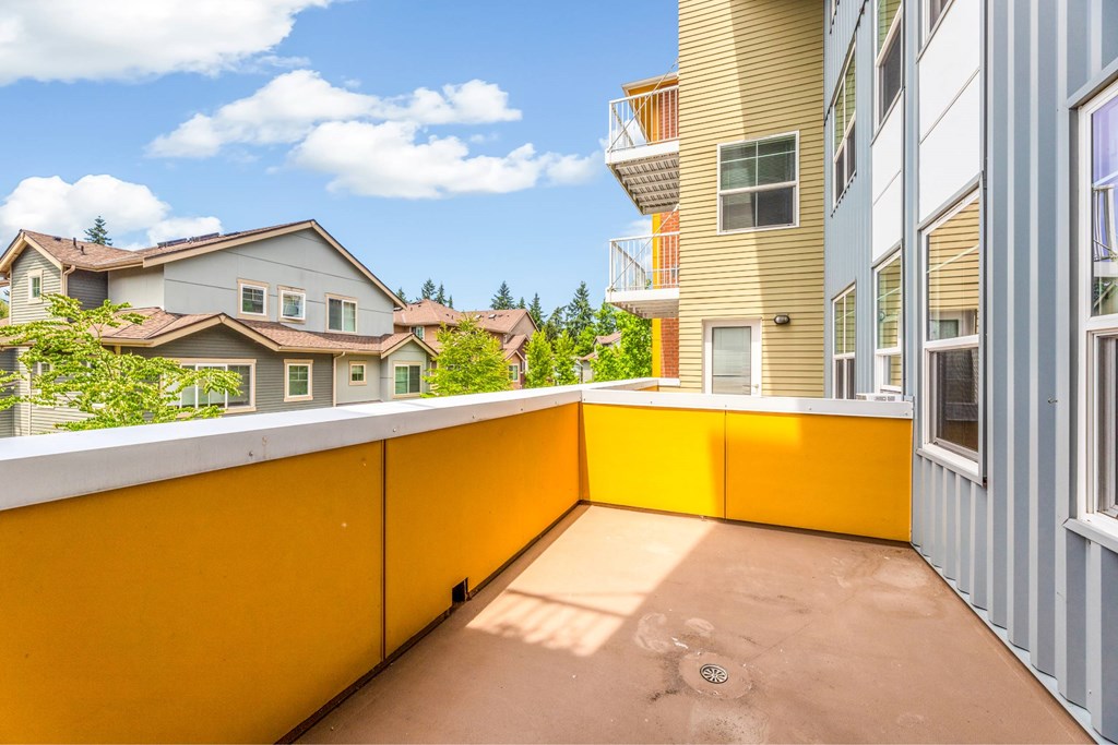 A balcony with a yellow railing overlooks a residential area.