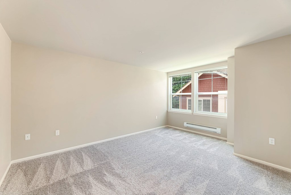 A room with a carpeted floor and a window showing a red building outside.