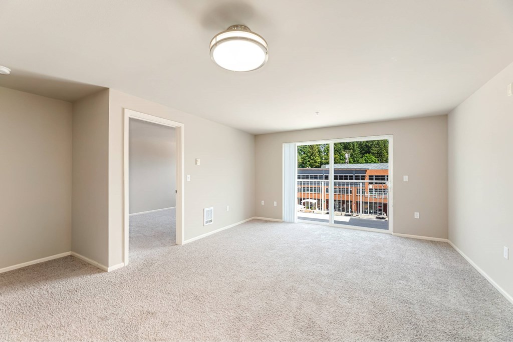 A spacious room with a carpeted floor and a window overlooking a construction site.