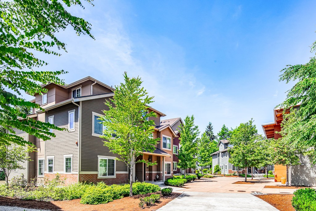 A row of houses with trees in front of them.