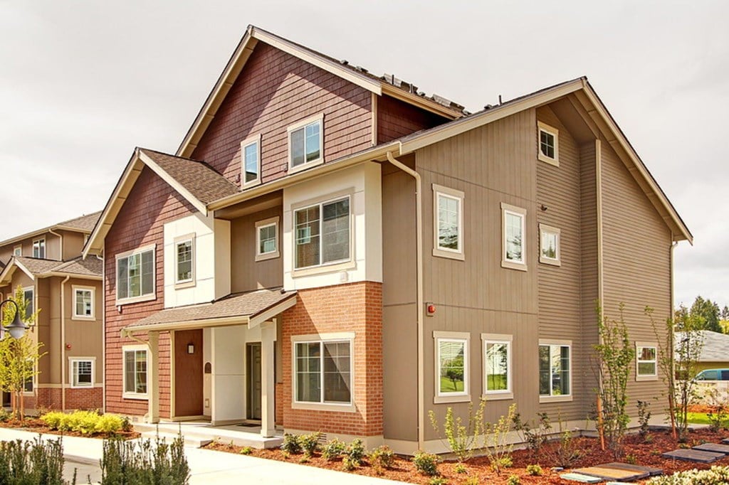 A modern two-story house with a red brick base and beige siding.