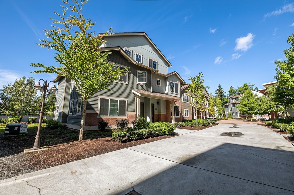 A residential area with a house and a tree in front.