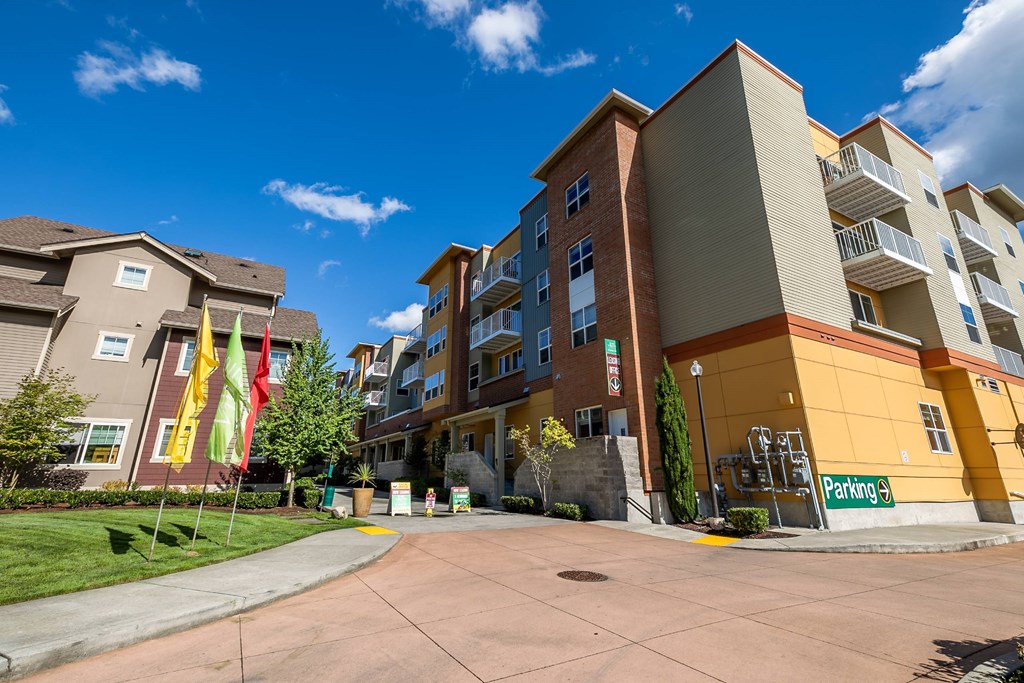 A parking lot in front of a multi-story apartment building.