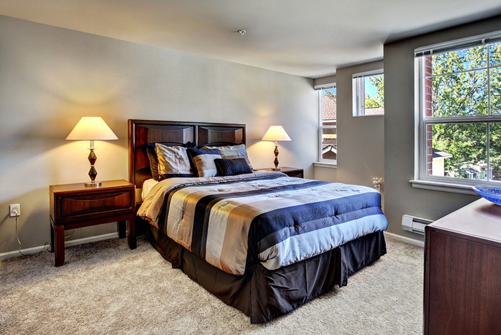 A bedroom with a large bed and two lamps.