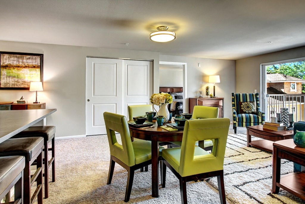 A dining room with a table set for two and green chairs.