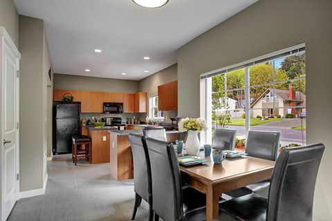 A kitchen with a table and chairs in front of a window.