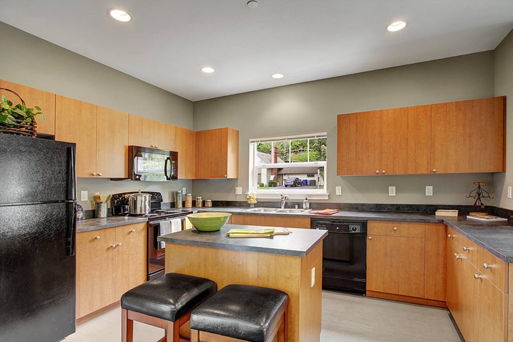 A kitchen with wooden cabinets and black appliances.