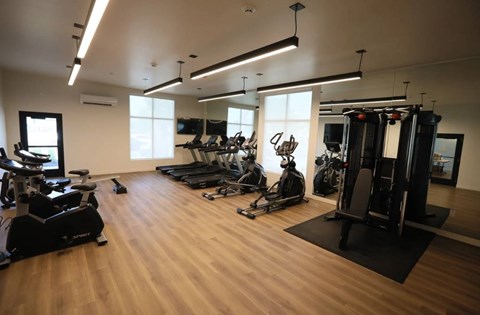 A gym with a variety of equipment including treadmills, stationary bikes, and weight machines.