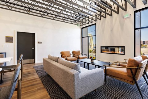 A living room with a grey couch and brown chairs.