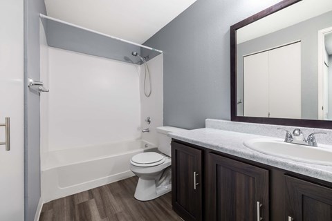 A white toilet sits in a bathroom with a white tub and a white sink.