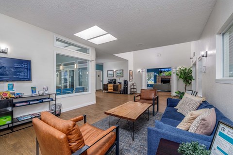 A living room with a blue couch and a brown leather chair.