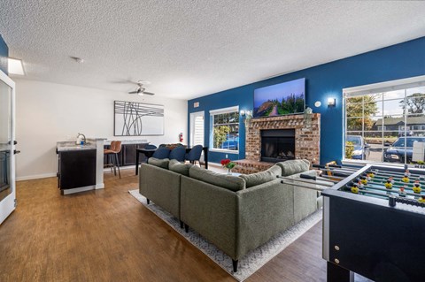 A living room with a grey couch, a fireplace, and a foosball table.