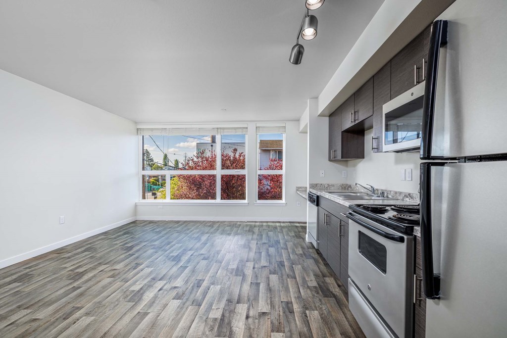 A kitchen with a stove top oven and a window with a view of a tree with red leaves.